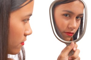 Unhappy Girl Looking At Her Reflection On The Mirror